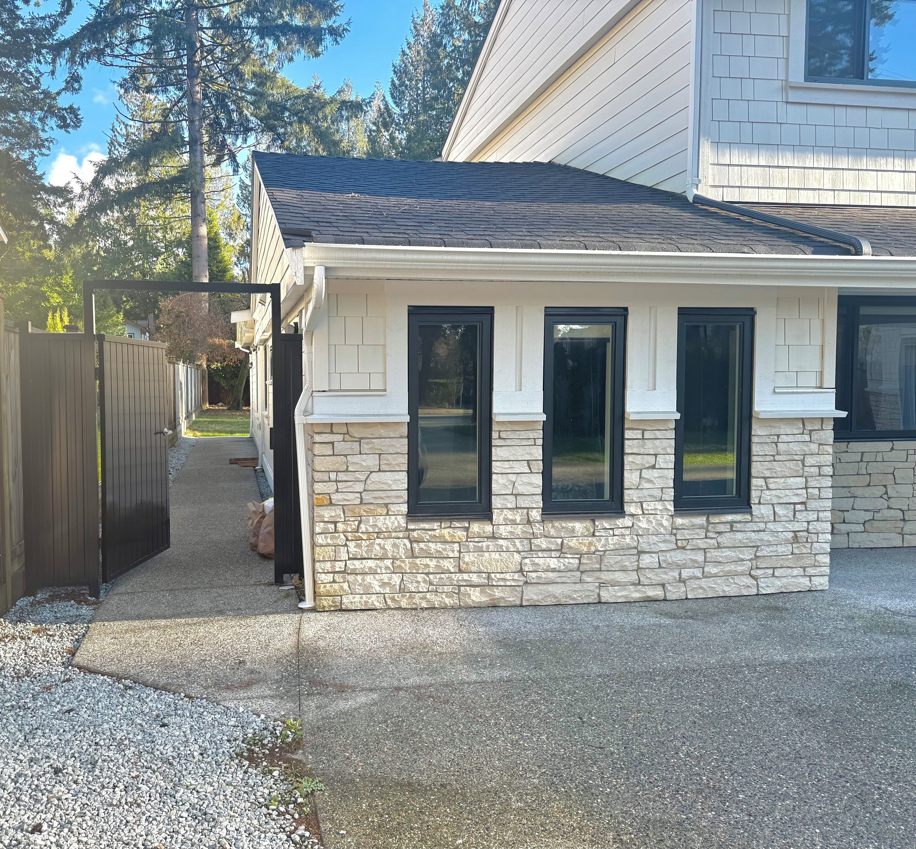 A house with a stone facade, three windows, and a wooden deck.