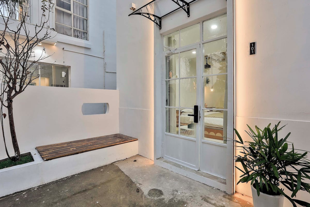 L’extérieur d’un bâtiment moderne, avec une porte en verre, un banc et un pot de fleurs.