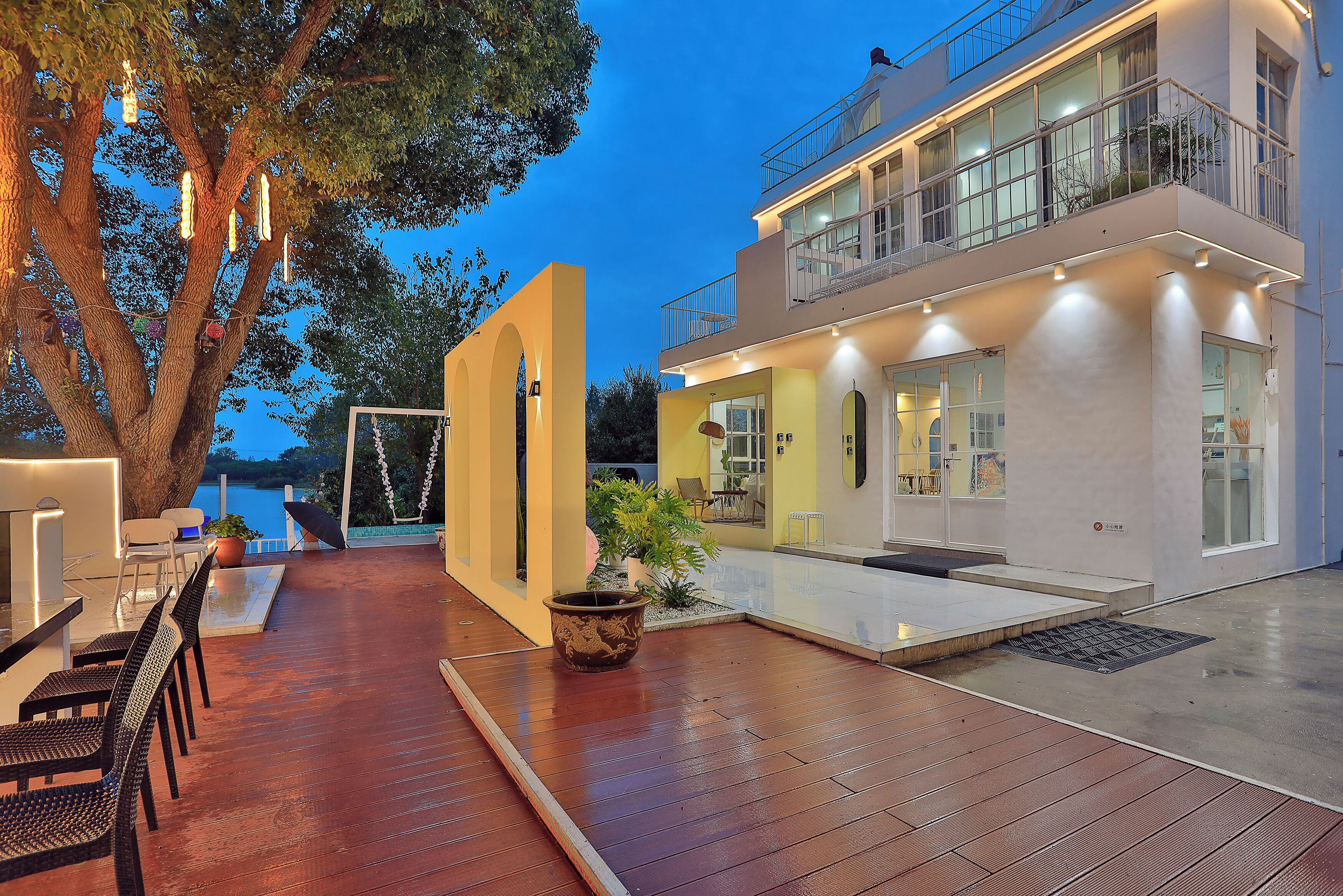 Uma casa moderna com deck de madeira, área de estar externa e uma grande árvore.
