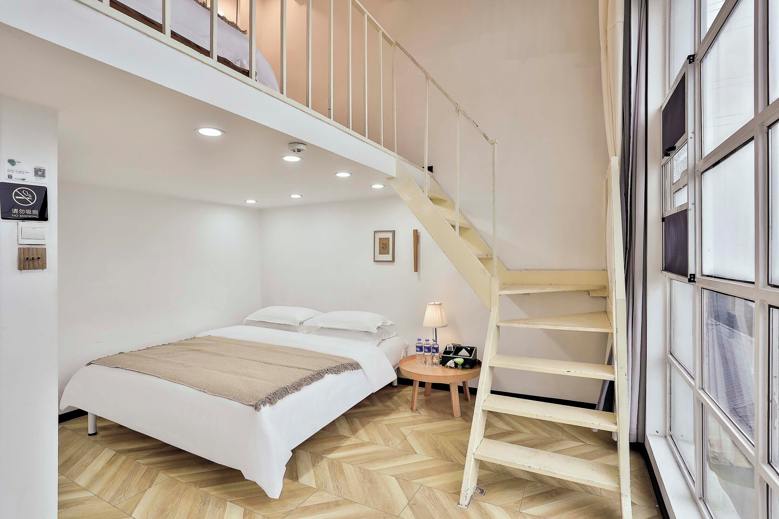 A bedroom with a bed, a nightstand, a lamp, and a wooden staircase.