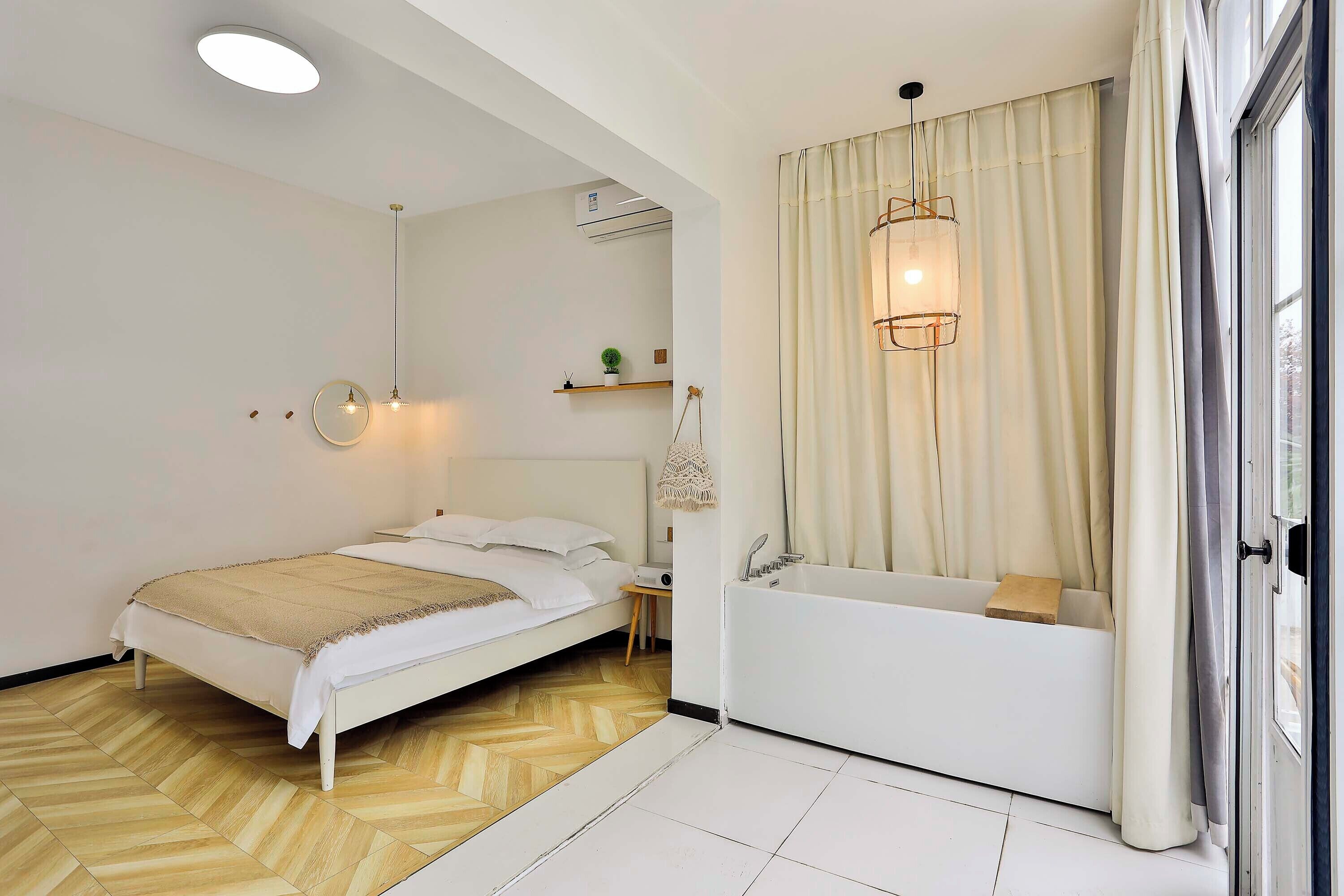 A bedroom with a bed, bedside table, and a built-in bathtub.