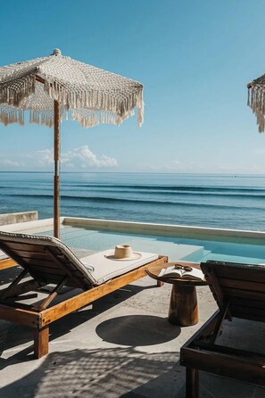 A poolside area with lounge chairs and umbrellas overlooking the ocean. - Tankah Arthouse, Tulum Beachfront – Chef Included (Tulum)