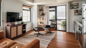 A modern living room with a flat-screen TV, leather sofa, and a dining area with a kitchen. - The Paloma by Homello | Quiet • Central • Perfect for Long Stays (Auckland)