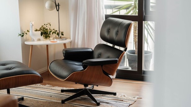A modern living room with a black leather armchair, a small round table with a white lamp, and a potted plant. - The Paloma by Homello | Quiet • Central • Perfect for Long Stays (Auckland)