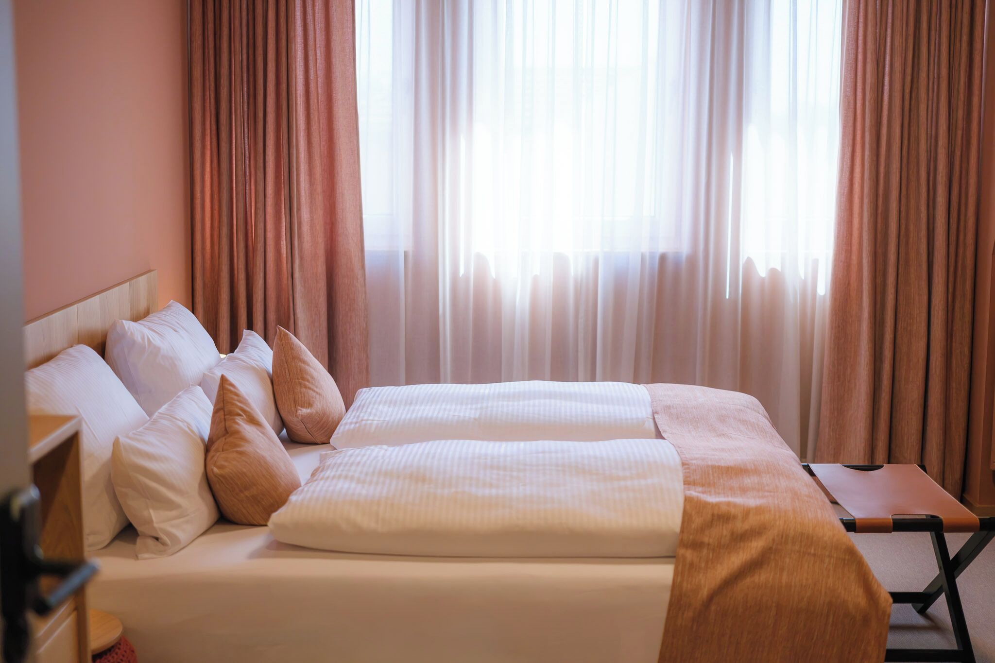 Una habitación de hotel con cama doble, mesita de noche y una silla.