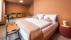 A hotel room with a large bed, bedside tables, a chair, a desk, and a wardrobe. - Haus Meeresstern (Wangerooge)