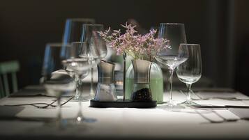 A table set with various glassware, including wine glasses and a vase with flowers.