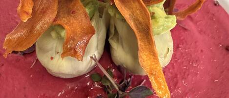 A dish with a vibrant red puree, garnished with crispy elements and microgreens.