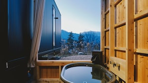 A wooden spa tub in a room with a large window overlooking a mountainous landscape. - BLANC YATSUGATAKE (Hokuto)
