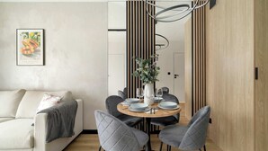 A modern dining area with a round table, grey upholstered chairs, and a white vase with flowers.