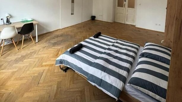 A room with a wooden herringbone floor, a bed with striped bedding, a desk with a chair, and three pendant lights. - Fantastic Inn Kraków - Krasińskiego (Kraków)