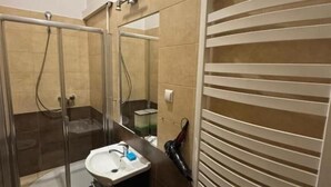 A bathroom with a glass-enclosed shower, a sink, and a towel rack. - Fantastic Inn Kraków - Krasińskiego (Kraków)