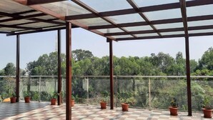 Un balcon abrité avec un sol à carreaux, des rampes en métal et des plantes en pot.