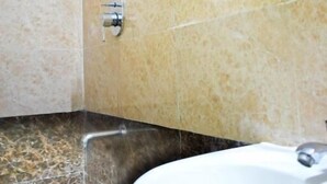 Une salle de bain avec un lavabo, un miroir et une pomme de douche.