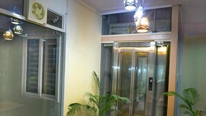 Un ascenseur avec des portes en verre, une plante en pot et un ventilateur de plafond.