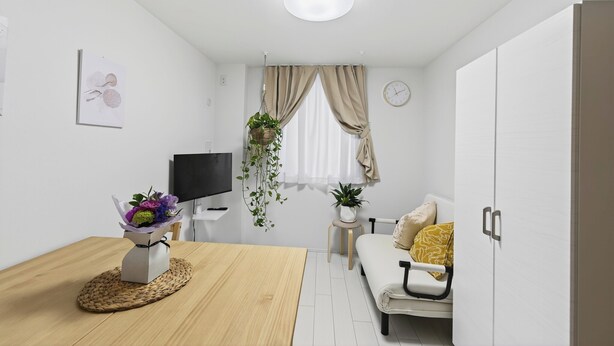 En moderne, minimalistisk stue med et træspisebord, en sofa, et fjernsyn og et vindue med gardiner.
