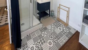 Une salle de bain avec une douche à parois de verre, un lavabo blanc et un carrelage décoratif.