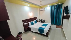 Une chambre d’hôtel avec un grand lit, un bureau, une chaise et un téléviseur fixé au mur.
