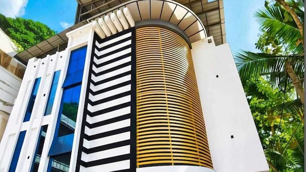 Un bâtiment moderne doté d’une façade incurvée, de grandes fenêtres et d’un mur orné de motifs.