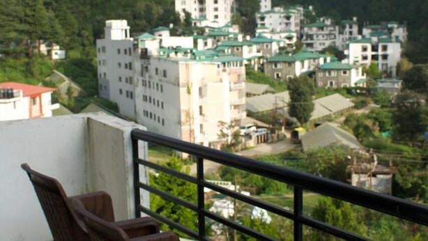 A balcony with two chairs, overlooking a residential area with buildings and greenery. - Hotel Dark Clouds (Sukha)