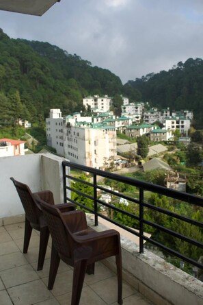 Un balcone con due sedie, affacciato su una zona residenziale con edifici e vegetazione.