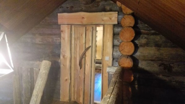 A wooden door with a metal handle, surrounded by stacked logs.