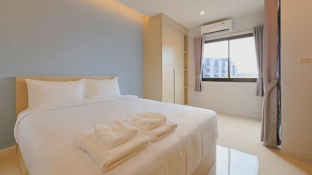 Een moderne hotelkamer met een groot bed, een kledingkast, een airconditioning en een raam met gordijnen.