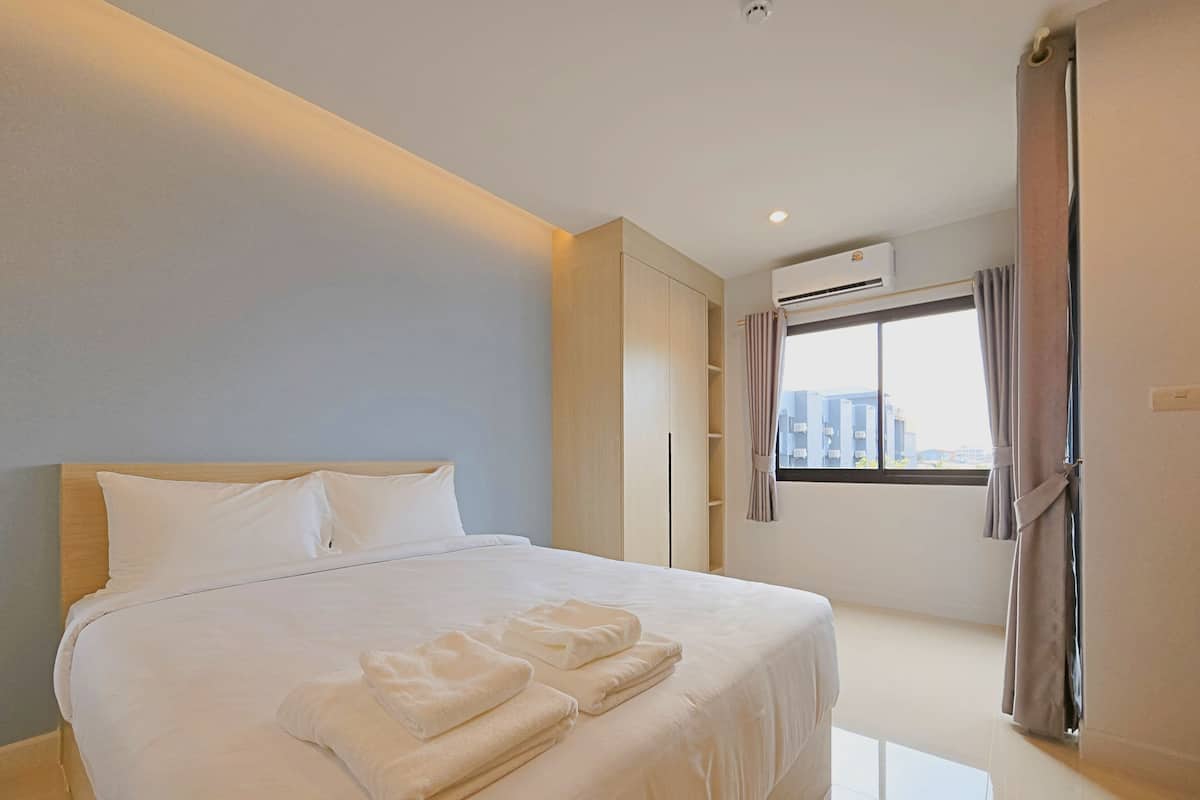 Een moderne hotelkamer met een groot bed, een kledingkast, een airconditioning en een raam met gordijnen.