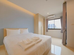 Een moderne hotelkamer met een groot bed, een kledingkast, een airconditioning en een raam met gordijnen.