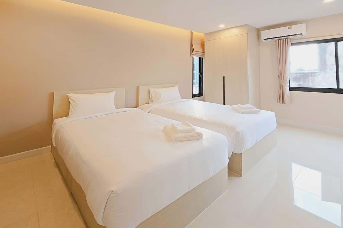 Hotelkamer met twee bedden, een groot raam met uitzicht, een airconditioning en een vlakke vloer.