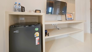 Een moderne keuken met een koelkast, een flatscreen televisie en een houten plank met waterflessen en een lijst met een foto.