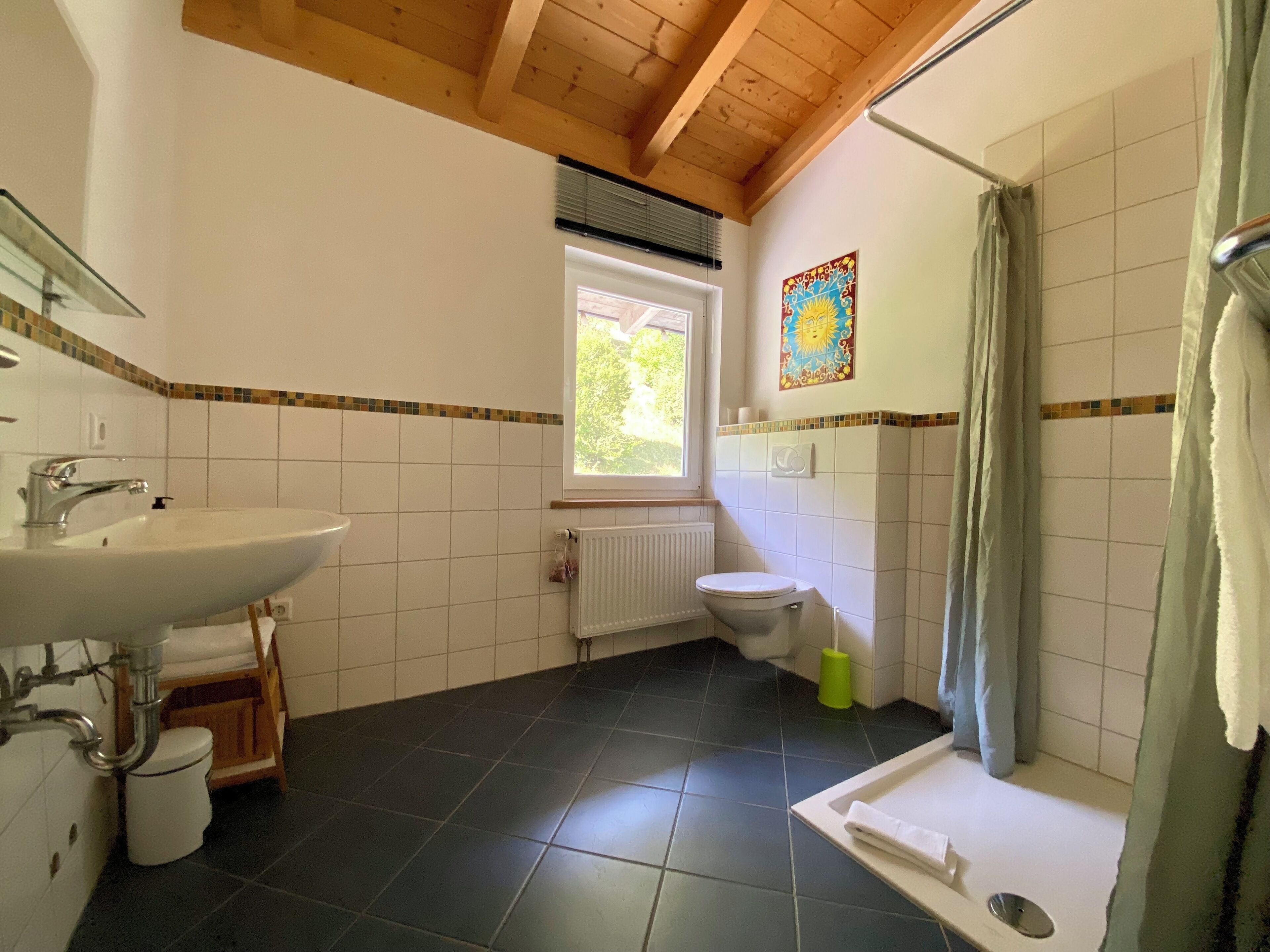 Une salle de bain avec un lavabo, des toilettes, une douche et une fenêtre.