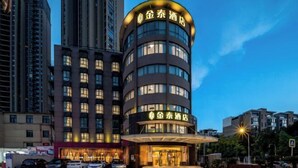 Un hotel moderno con fachada curva, varios pisos y señalización iluminada.