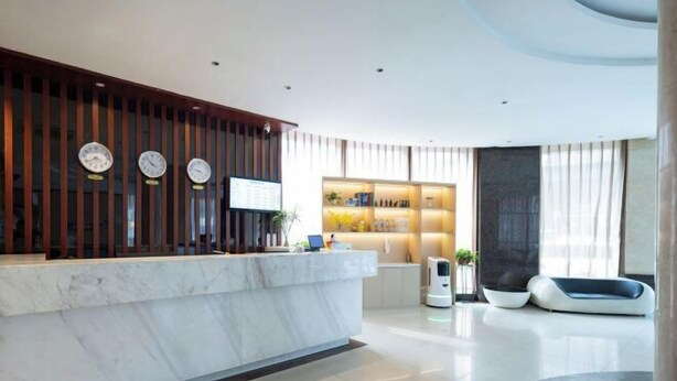 Un área de recepción moderna con mostrador de mármol, paneles de madera y una pantalla digital.