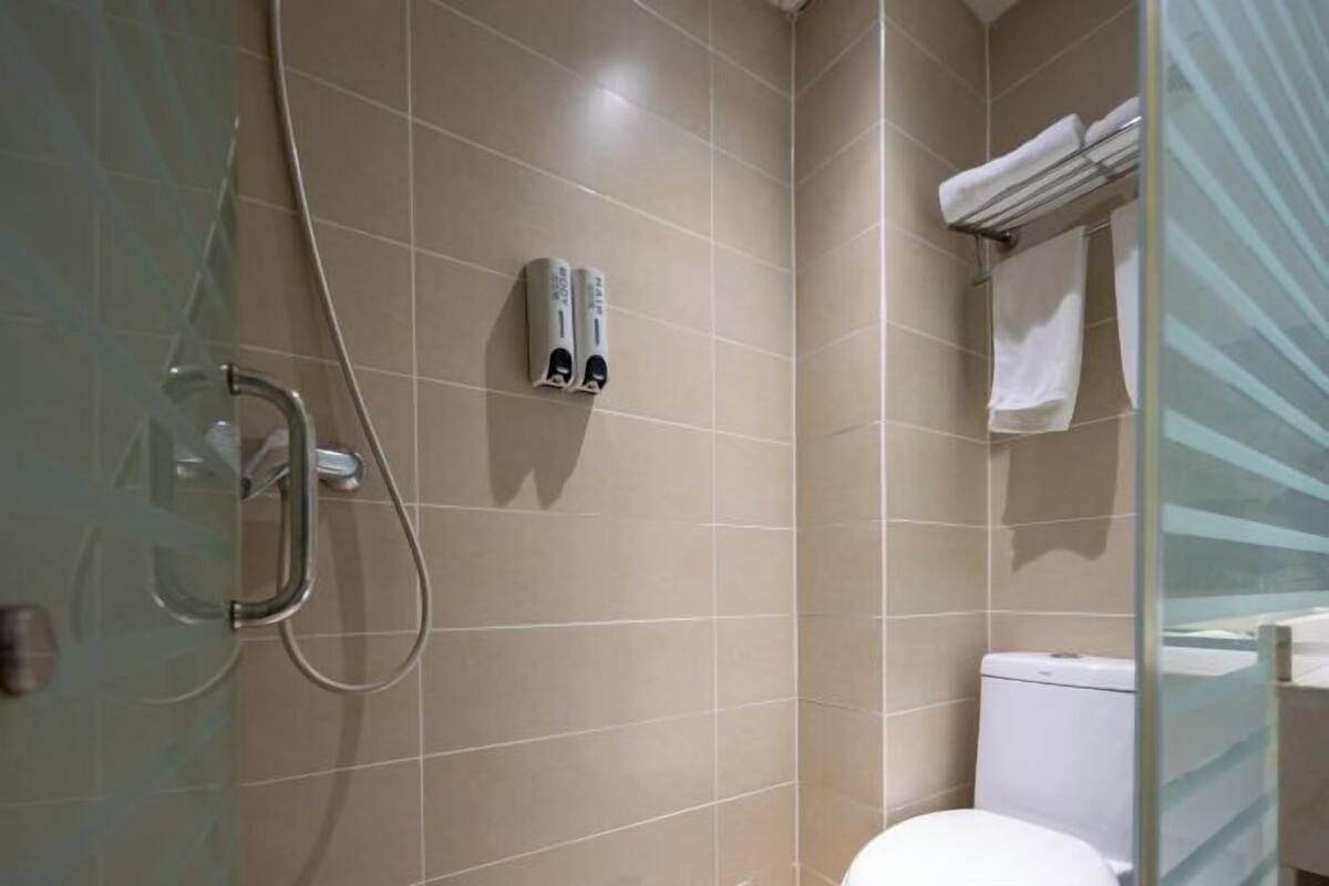 A bathroom with a glass shower enclosure, a toilet, and a towel rack.
