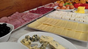 Un buffet con diverse pietanze tra cui carni, formaggi e frutta.