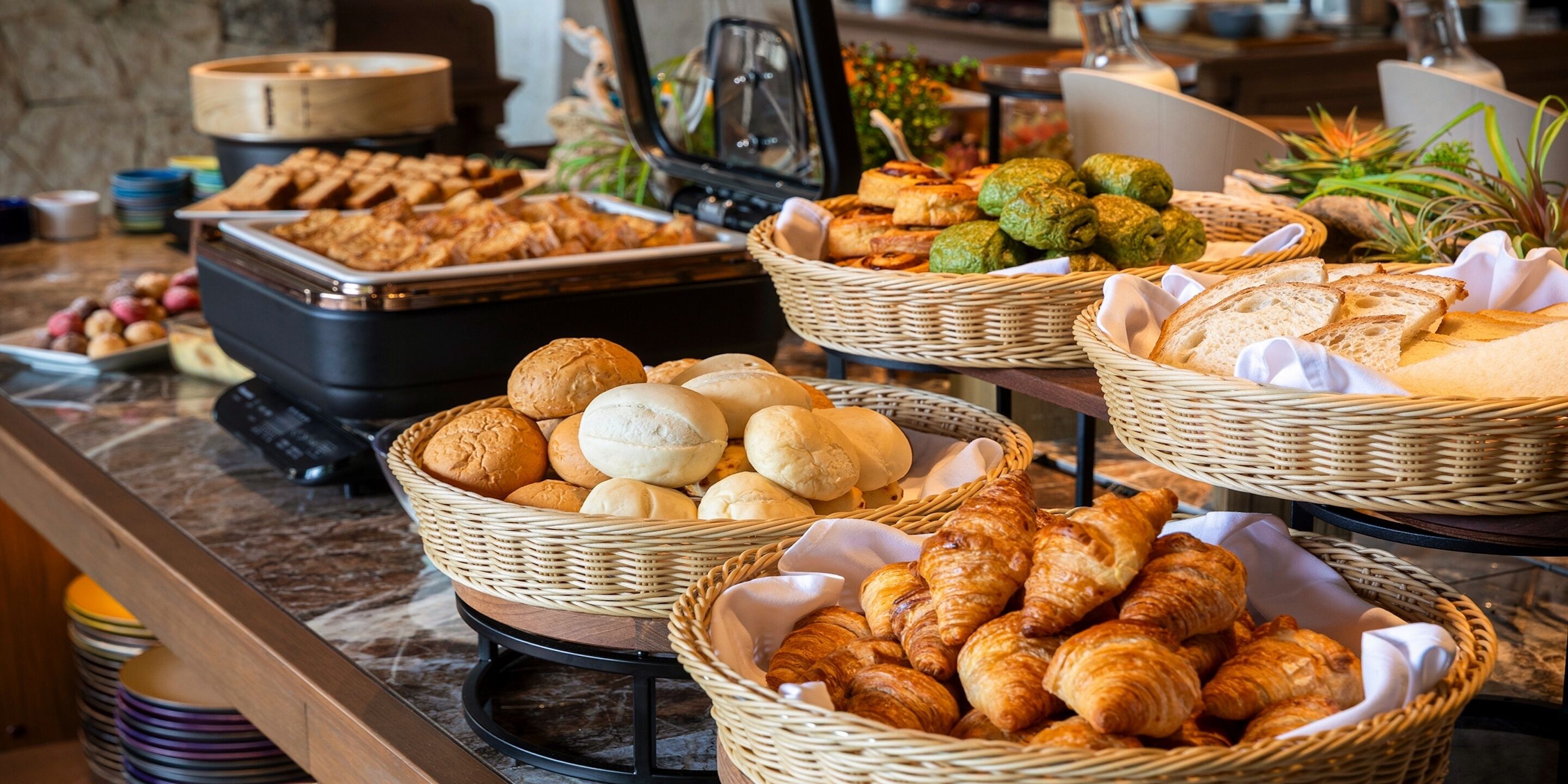 A buffet with various baked goods including bread, rolls, and pastries.
