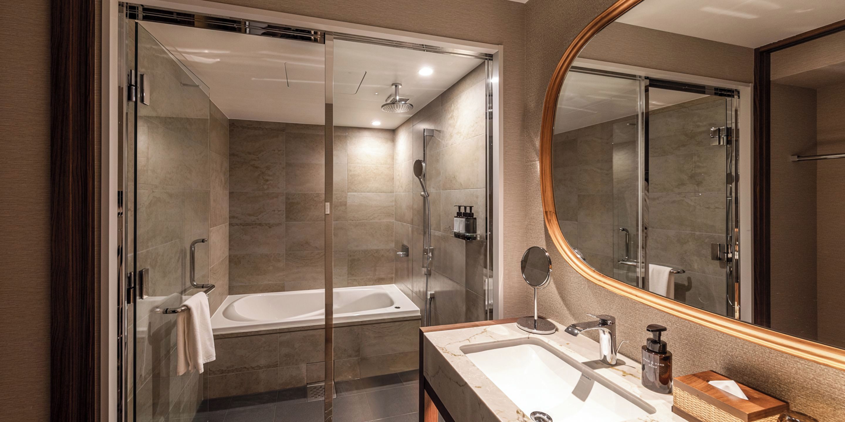 Un bany modern amb dutxa de vidre, banyera independent i un lavabo amb mirall.