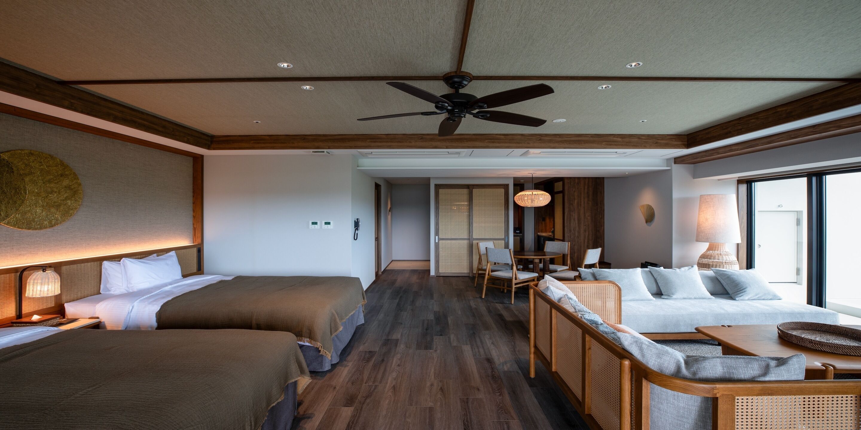 A hotel room with two beds, a dining area, and a sofa.