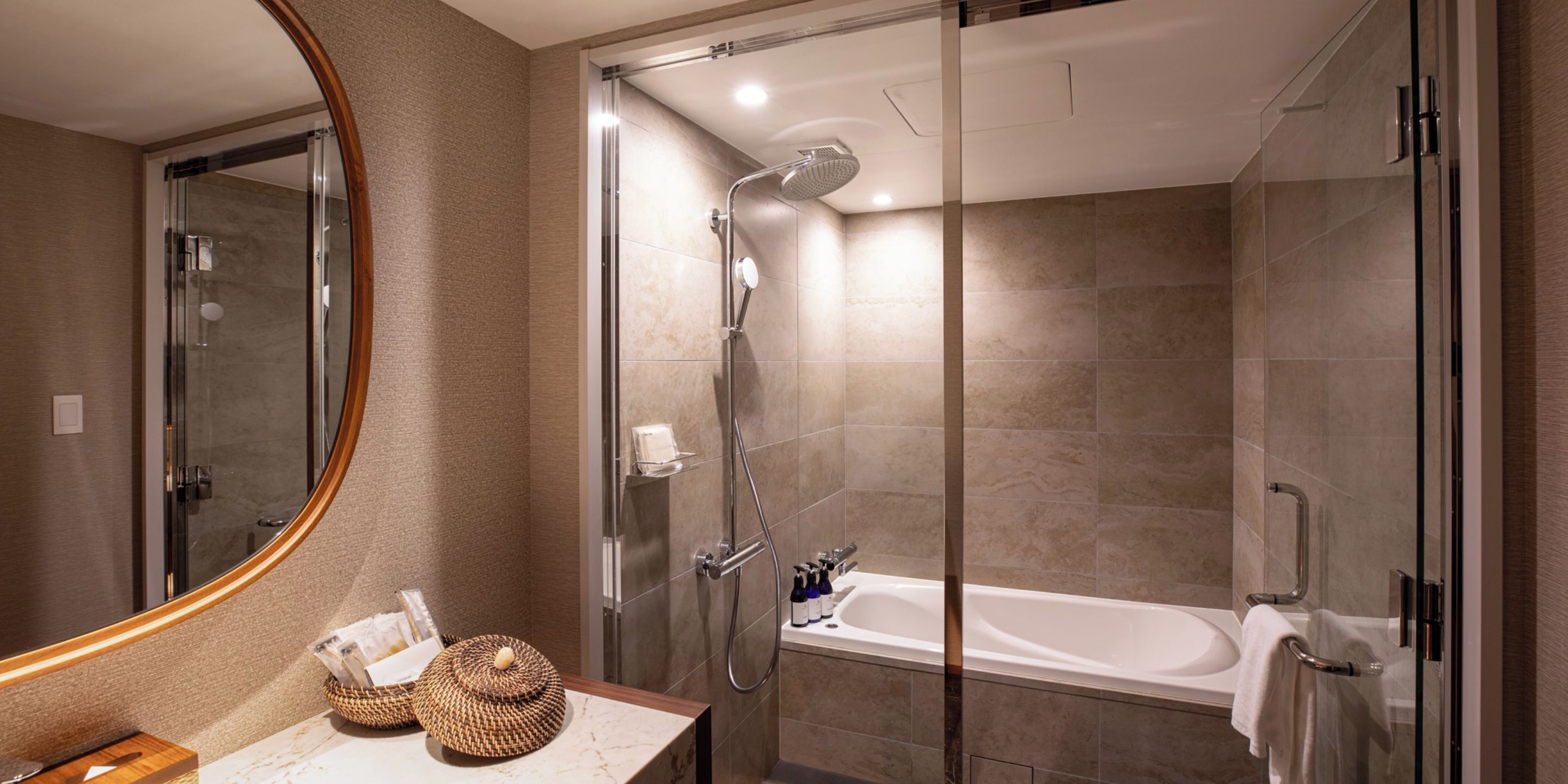 Ein modernes Badezimmer mit einer gläsernen Dusche, einer Badewanne und einem Waschtisch mit Spiegel.