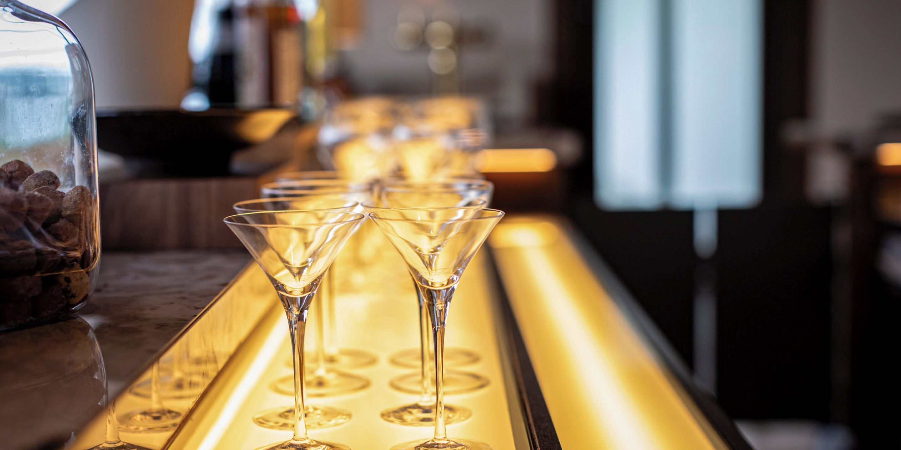 A bar with multiple martini glasses lined up on a tray.