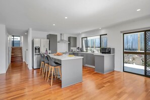 A modern kitchen with a central island, grey cabinetry, and a wooden floor. - Goonawarra Getaway at Mooloolaba (Mooloolaba)