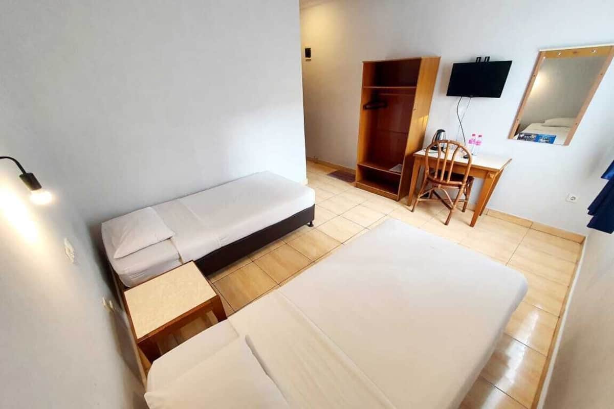 Una habitación pequeña y limpia con cama, escritorio, silla, armario y televisor montado en la pared.
