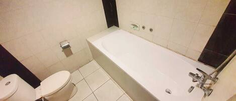 Un baño con bañera, inodoro y espejo.