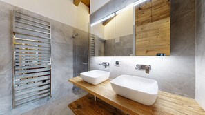 Een moderne badkamer met twee witte wasbakken, een houten wastafelmeubel en een grote spiegel.