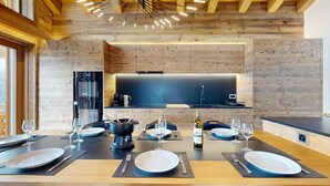 Una cocina moderna con armarios de madera, encimera negra y zona de comedor para cuatro personas con una isla central.