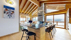Una cocina moderna con una isla central, ventanas amplias y una chimenea de piedra.