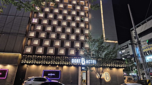 Ein modernes Hotel mit einer Anordnung beleuchteter Fenster und einem gut sichtbaren Schild mit der Aufschrift "DORT HOTEL".