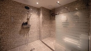 Ein moderner Duschbereich mit Glastrennwand, einer integrierten Ablage für Toilettenartikel und einer Duschbrause.