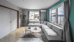 A modern living room with a sectional sofa, a coffee table, and a view of the outside. - THE KAMUY FURANO (Nakafurano)